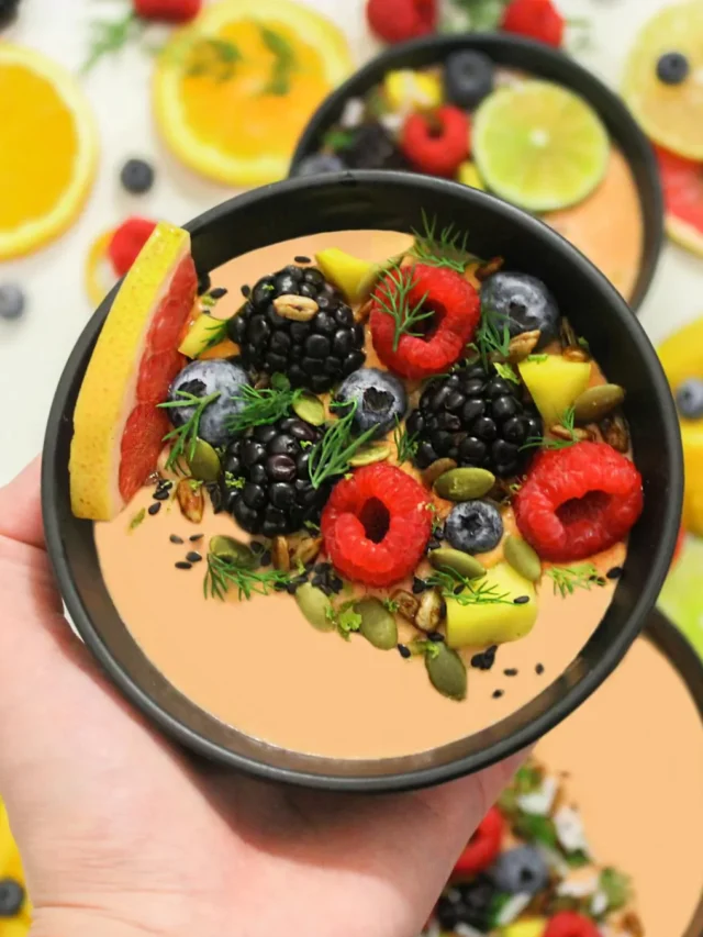 Top view of anti-inflammatory diet foods including salmon, berries, leafy greens, turmeric, olive oil, nuts, and green tea on a wooden table.