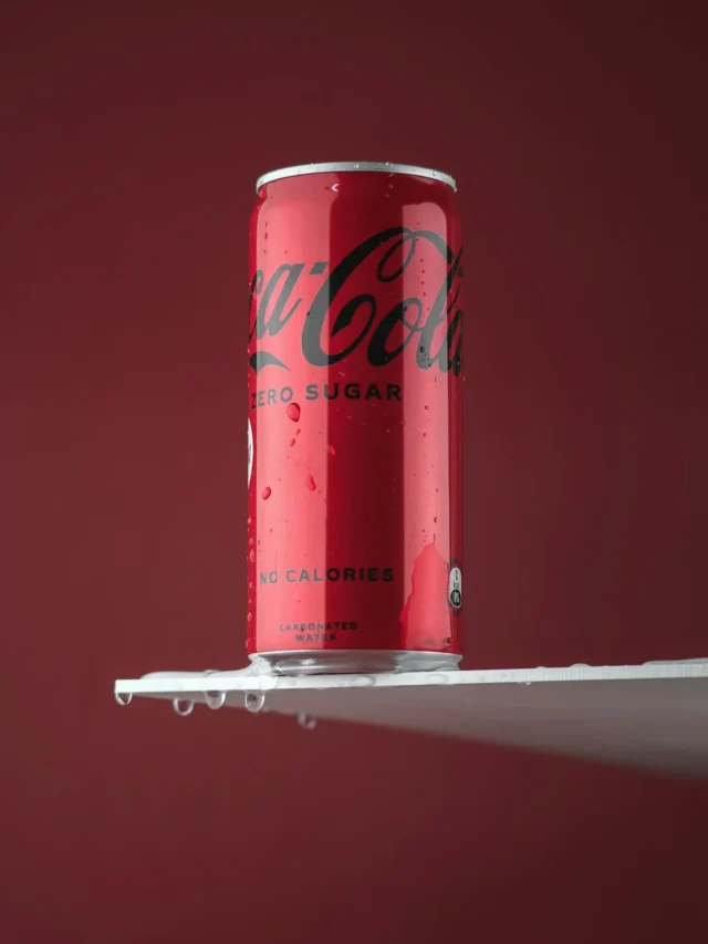 Creative flat lay of a Diet Coke can with ice cubes and caffeine molecule illustration in the background, hinting at a hidden ingredient.